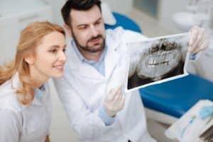 Lee Family Dentistry provides a comprehensive solution for dental care, without high prices or long waits. They offer premium dental services at competitive prices in just minutes! Image of dentists and smiling woman patient looking at x-rays.