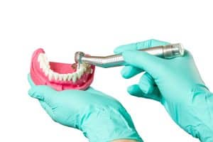 Dental restoration is a solution to help bring your teeth up to standard, keeping you from feeling embarrassed and ashamed of your smile. Image of dentist demonstrating work on a set of teeth.