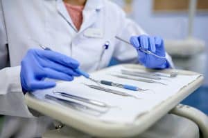 With Lee Family Dentistry you won't have to choose between saving your teeth and saving your finances. With Lee Family Dentistry, our patients know that we always strive for the best possible treatment without overloading them. Image of dentist and tray of dental tools.